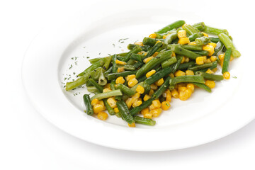 Green beans with corn on a white plate on a white bacgraund. View from above. 