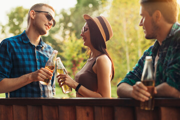 Group of young friends relaxing in nature on a summer sunny day, celebrating drinking drinks, celebration concept