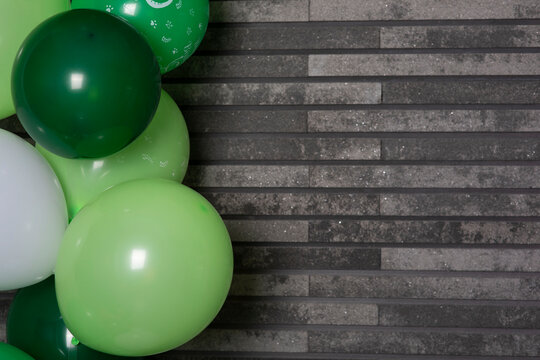 Grauer Steinhintergrund, auf der linken Seite mit vielen gr&uuml;nen Luftballons f&uuml;r ein Geburtstag geschm&uuml;ckt,  geflieste in Blocke Wand aus dem schmalen Stein. Sehr gut geeignet als Hintergrund f&uuml;r diver