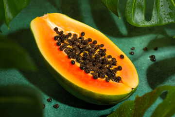 Fresh half of papaya with seeds on tropical leaves background. Tropical exotic fruit. - obrazy, fototapety, plakaty