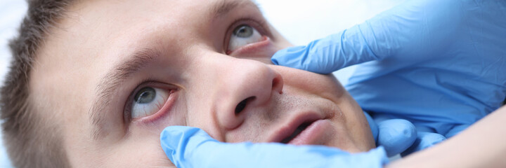 Doctor with gloves examining mucous membrane of patients eye