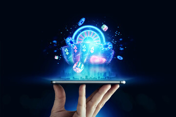 Creative background, online casino, in a man's hand a smartphone with playing cards, roulette and chips, black-neon background. Internet gambling concept. Copy space.