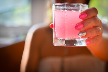 girl holding a glass with a pink cocktail