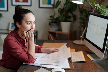 Young woman analyzing design sketch on computer