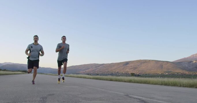 two men run on the road surrounded by nature