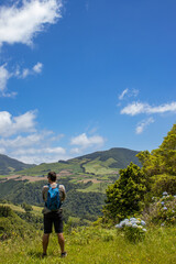 Hiker enjoying view, landscape at Azores islands, hydrangeas, hills.