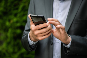 Man in a gray suit with a smartphone.