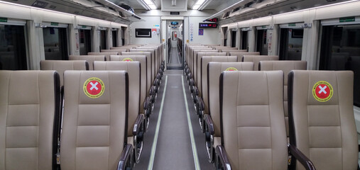 Photo of an empty train carriage aisle, with a no-seat sign sticker, to maintain a distance between passengers during the COVID-19 pandemic, one of Indonesia's railway policies. Jakarta (2020-12)