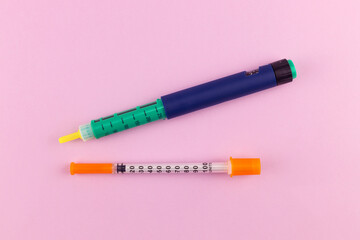 Insulin pen and insulin syringe on pink background