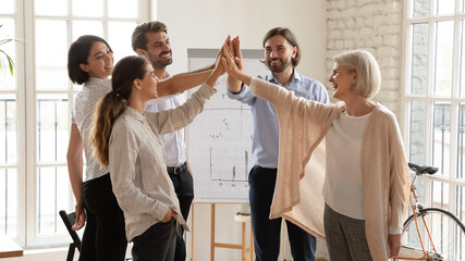Happy smiling multiethnic business people giving high five at meeting, celebrating shared business success or achievement, good teamwork result, laughing employees team engaged in team building