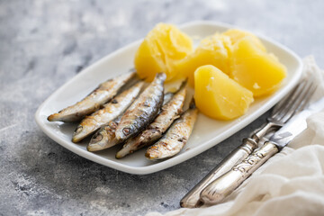 fried sardines with boiled potato on white dish