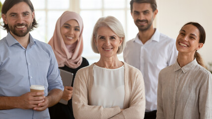 Head shot portrait smiling multiethnic employees group with mature businesswoman executive team leader looking at camera, happy diverse colleagues posing for photo in office, unity and cooperation