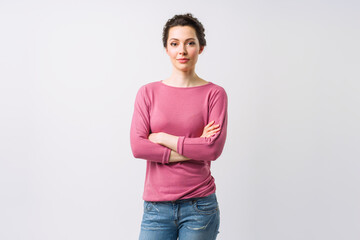 Young woman portrait. Adorable brunette in a sweater looking at the camera with her arms crossed.