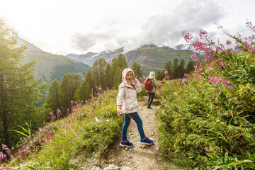Children hiking in Alps mountains. Kids look at snow covered mountain. Spring family vacation....
