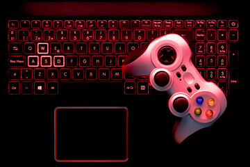 Teclado de portátil retroiluminado gamer y un mando joystick de videojuegos.