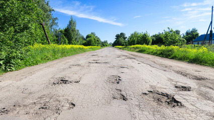 The texture of cracked old asphalt in need of repair. The road is full of holes and potholes. Pit...