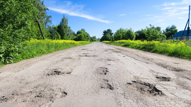 The texture of cracked old asphalt in need of repair. The road is full of holes and potholes. Pit repair