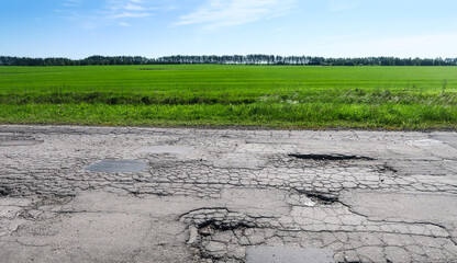 The texture of cracked old asphalt in need of repair. The road is full of holes and potholes. Pit repair