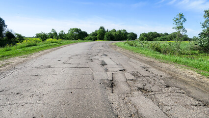 The texture of cracked old asphalt in need of repair. The road is full of holes and potholes. Pit...