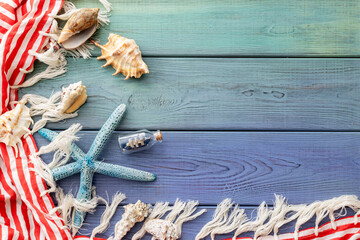 summer background: fringed pareo, seashells, boat in a bottle, starfish on a blue wooden background