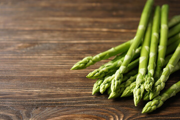 Fresh asparagus on wooden background, place for text.