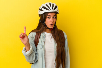 Young student caucasian woman wearing a bike helmet isolated on yellow background having some great idea, concept of creativity.