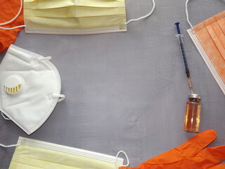 on a gray background, a vaccine, a syringe, orange medical masks and gloves. High quality photo