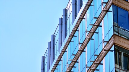 Abstract closeup of the glass-clad facade of a modern building covered in reflective plate glass. Architecture abstract background. Glass wall and facade detail.