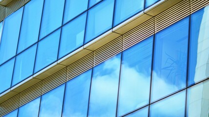 Obraz premium Abstract closeup of the glass-clad facade of a modern building covered in reflective plate glass. Architecture abstract background. Glass wall and facade detail.