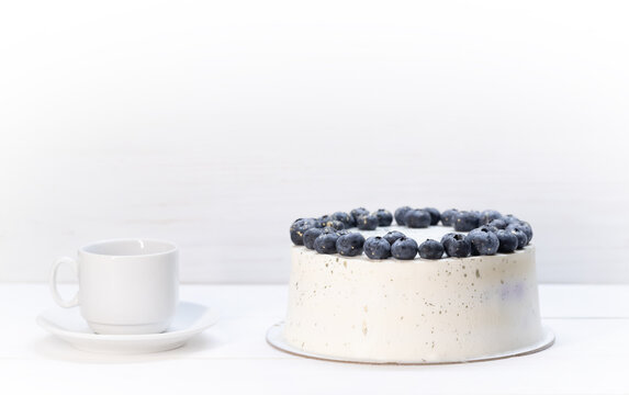 White curd torso with blueberry decoration.next to a white cup and saucer.space for text. High quality photo