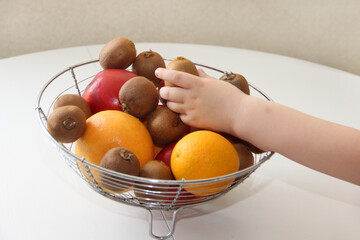 A bowl of fruit. The child takes fruit from a vase and different fruits