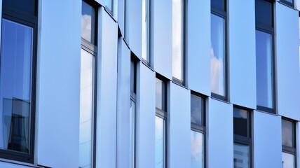 Obraz premium Abstract closeup of the glass-clad facade of a modern building covered in reflective plate glass. Architecture abstract background. Glass wall and facade detail.