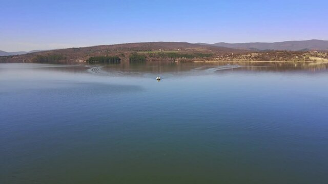 Moving fishing motorboat at the lake. Aerial view of drone forward. Summer tourism