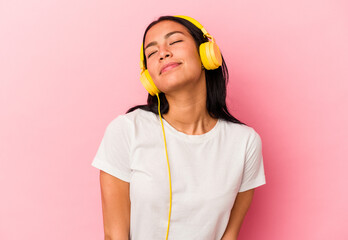 Young Venezuelan woman listening to music isolated on pink background dreaming of achieving goals...