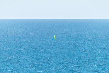 Naklejka premium Sailboat sailing alone in vast blue Gulf of Mexico off the coast of Panama City Beach Florida