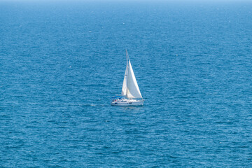 Sailboat sailing alone in vast blue Gulf of Mexico off the coast of Panama City Beach Florida
