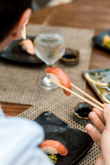 Fototapeta na wymiar Delicious Sushi Menu Food Sashimi Salmon Tuna Shrimp Hashi Holds Gourmet Plate Restaurant Wooden Table