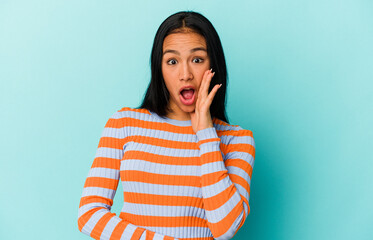 Fototapeta premium Young Venezuelan woman isolated on blue background shouts loud, keeps eyes opened and hands tense.