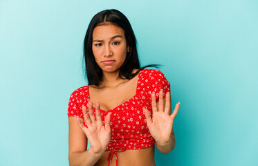 Young Venezuelan woman isolated on blue background rejecting someone showing a gesture of disgust.