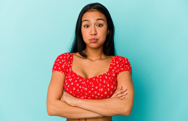 Young Venezuelan woman isolated on blue background blows cheeks, has tired expression. Facial...