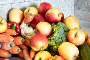 Concept of a healthy diet, a minimum of calories, vegetarian, vitamins. Fresh vegetables, fruits lie beautifully in the kitchen. Broccoli, carrots, zucchini, apples, peppers. Day light. Farm products.