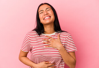 Fototapeta premium Young Venezuelan woman isolated on pink background laughs happily and has fun keeping hands on stomach.