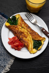 Egg omelette with spinach and tomate on dark background. French food