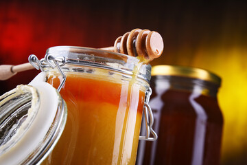 Composition with stick and open jar of honey