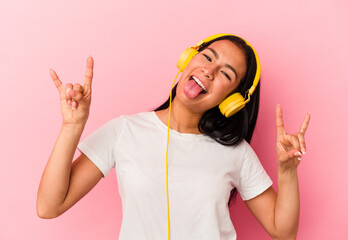 Young Venezuelan woman listening to music isolated on pink background