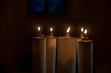 Fototapeta kilka płonących świec w kościele, pośród mroku obraz