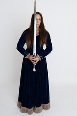 Medieval woman in a blue velvet dress holding a weapon
