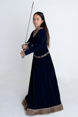 Medieval woman in a blue velvet dress holding a weapon