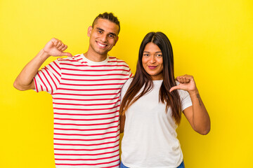 Young latin couple isolated on yellow background feels proud and self confident, example to follow.