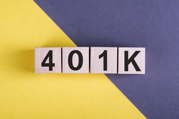 Word 401k on wooden cubes, over yellow and blue background. Business and finance concept. Retirement Plan.